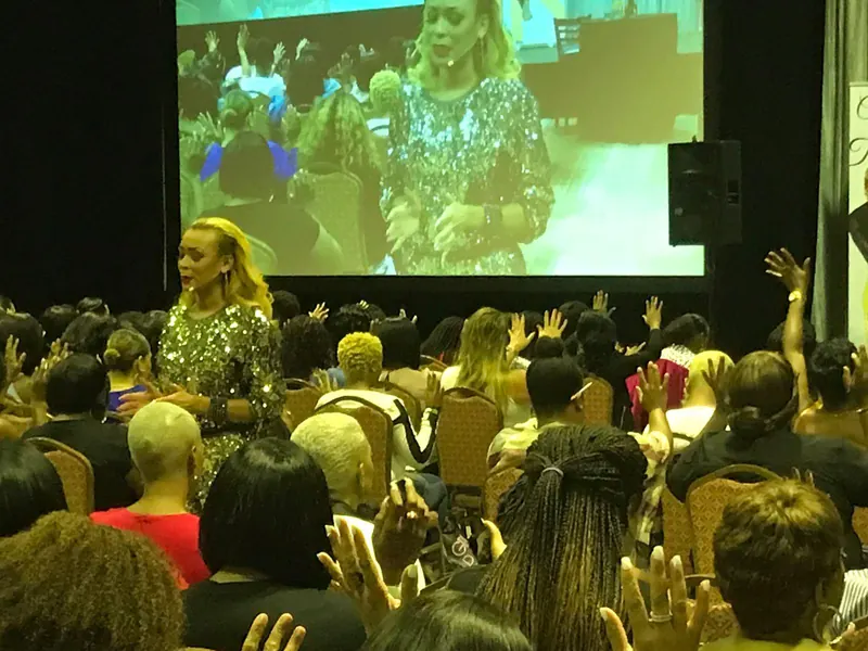 Ayesha leading a room of women with hands raised